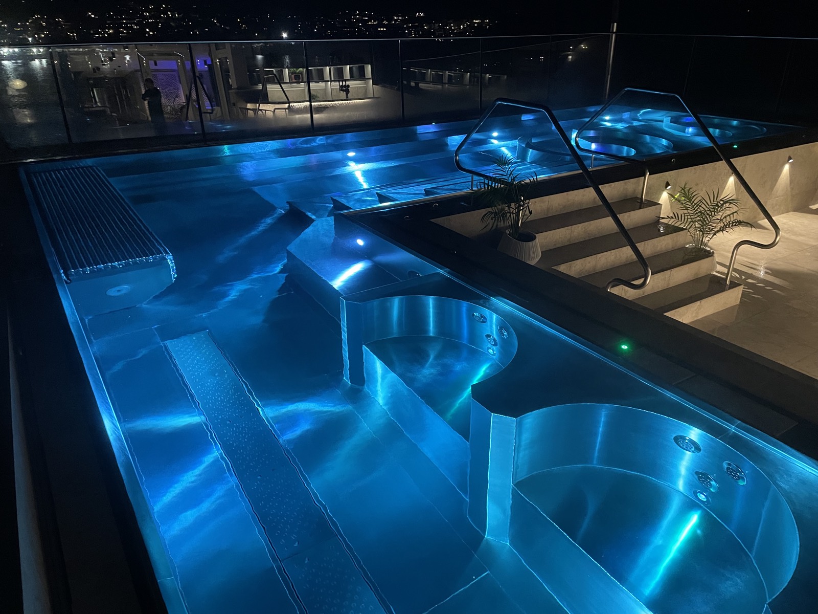 Large lit stainless steel spa complex at night